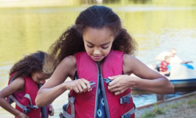 Two children put on life vests next to a lake