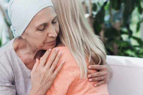 An older woman wearing a head scarf hugs her adult daughter.