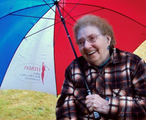 A smiling elderly woman holding an umbrella