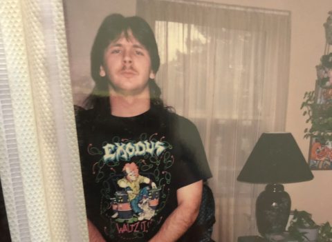 Young man poses in his living room wearing a rock band t-shirt.