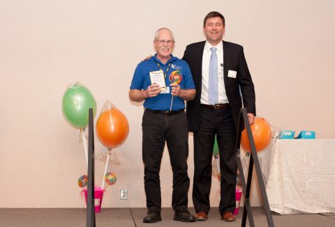 Phil Cahoon being given an award with ballons around him and the presenter