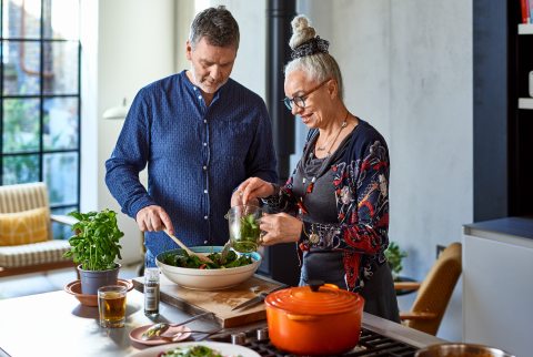 A man and a woman preparing food in a well-lit kitchen