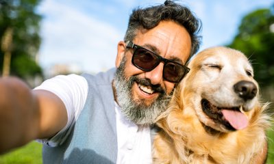 Man wearing sunglasses taking a selfie with his golden retriever.