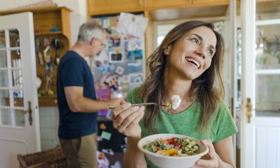 Middle aged woman happily eats a bowl of vegetables