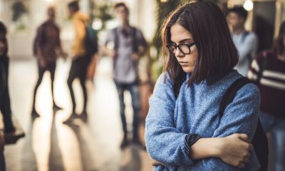 Worried teenage girl wearing backpack at school.