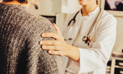 A smiling healthcare provider placing a hand on a patient's shoulder as a gesture of comfort