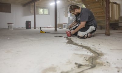 Kneeling man works to seal cracks in floor of basement