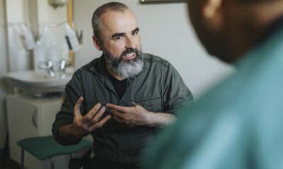 Bearded man talks expressively with a provider in an exam room