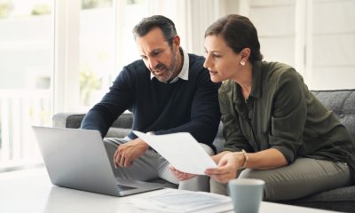 Male and female looking at computer and important documents.