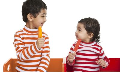 Two children in striped shirts enjoy popsicles