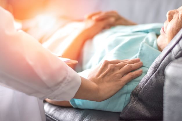 A caregiver gently places their hand on the shoulder of a sleeping patient.