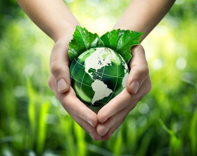 Hands cradling Earth with green grass in background