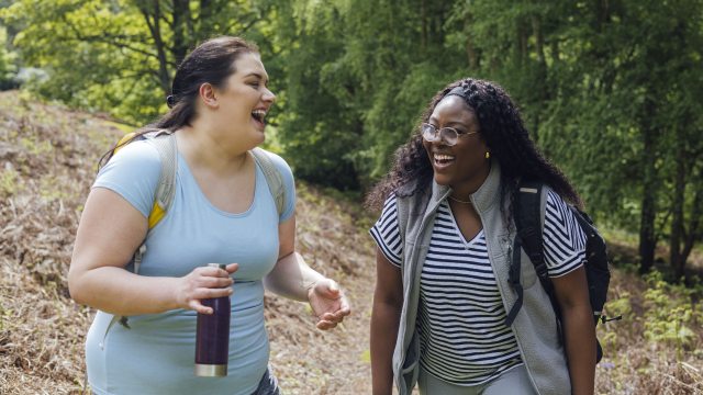 Two women share a laugh while walking outdoors