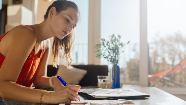Woman writes notes on paper at coffee table