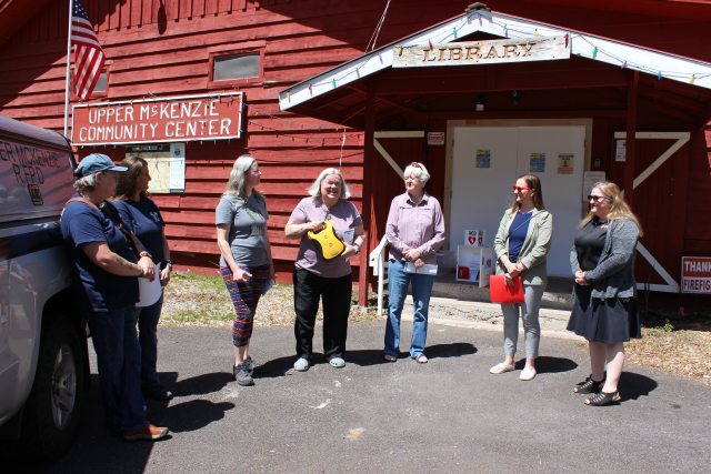 People stand in front of the Upper McKenzie Community Center during a ceremony to donate an automated defibrillator device.