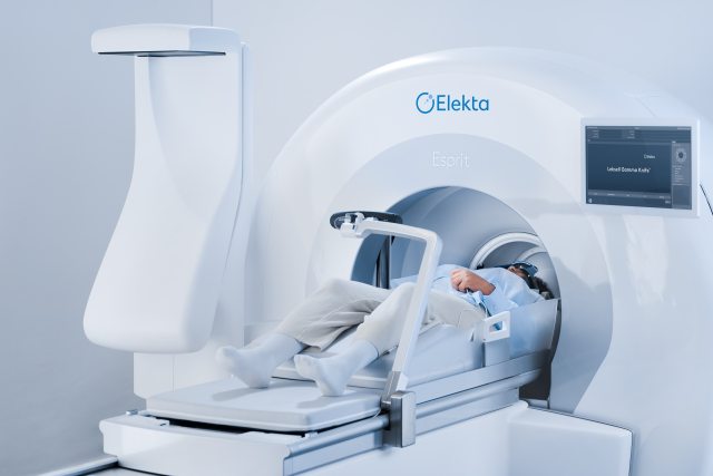 An image of a person laying down, partially inside the Gamma Knife machine, which is shaped like a circle.