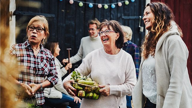 Three women, smiling, talking and laughing at a farmer's market