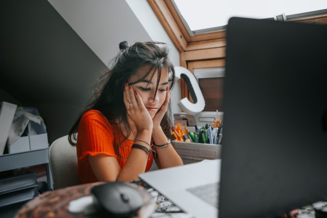 Young woman looking stressed sitting in front of her computer.