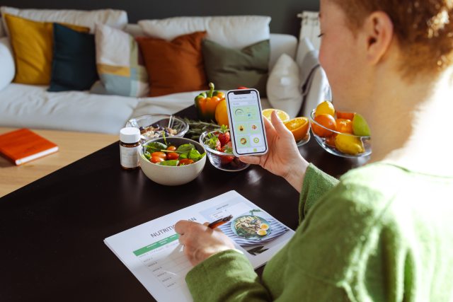 Looking over the shoulder of a redhaired woman using a meal planning app